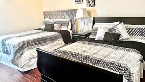 A hotel room with two beds, a nightstand, a lamp, and artwork on the wall.