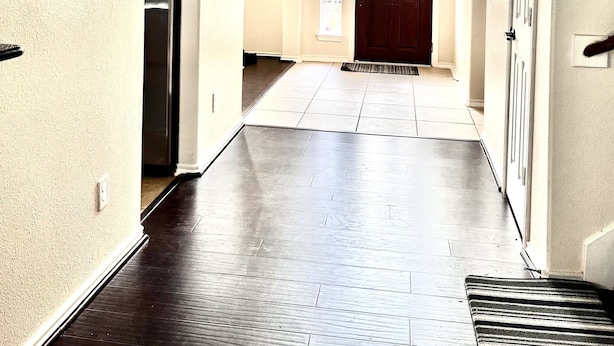 A spacious hallway with a wooden floor, a large mirror, and a door with a window above it.