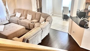 A living room with a sectional sofa, ottoman, and a ceiling fan.