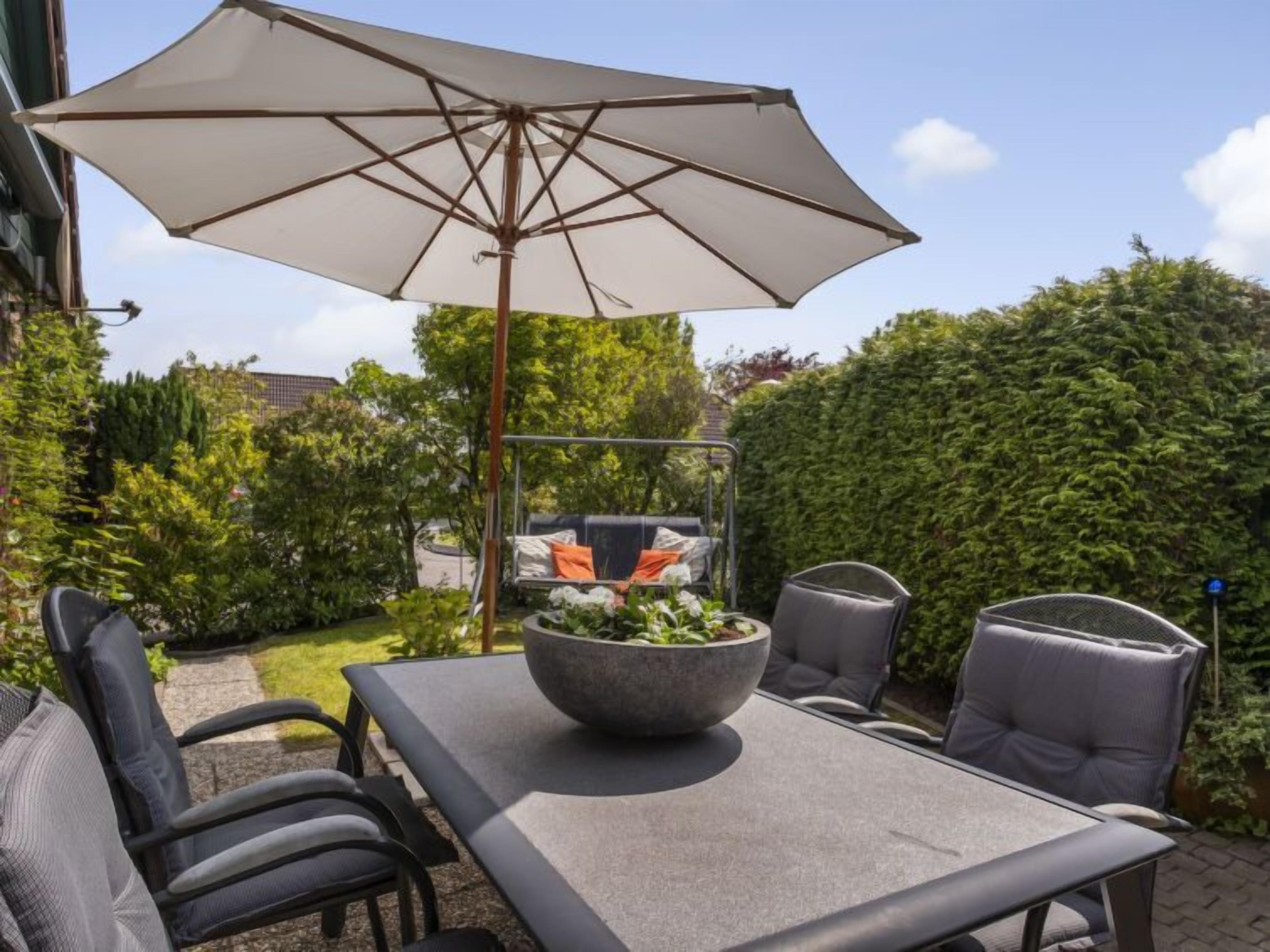 An outdoor patio with a table, chairs, and a large umbrella.