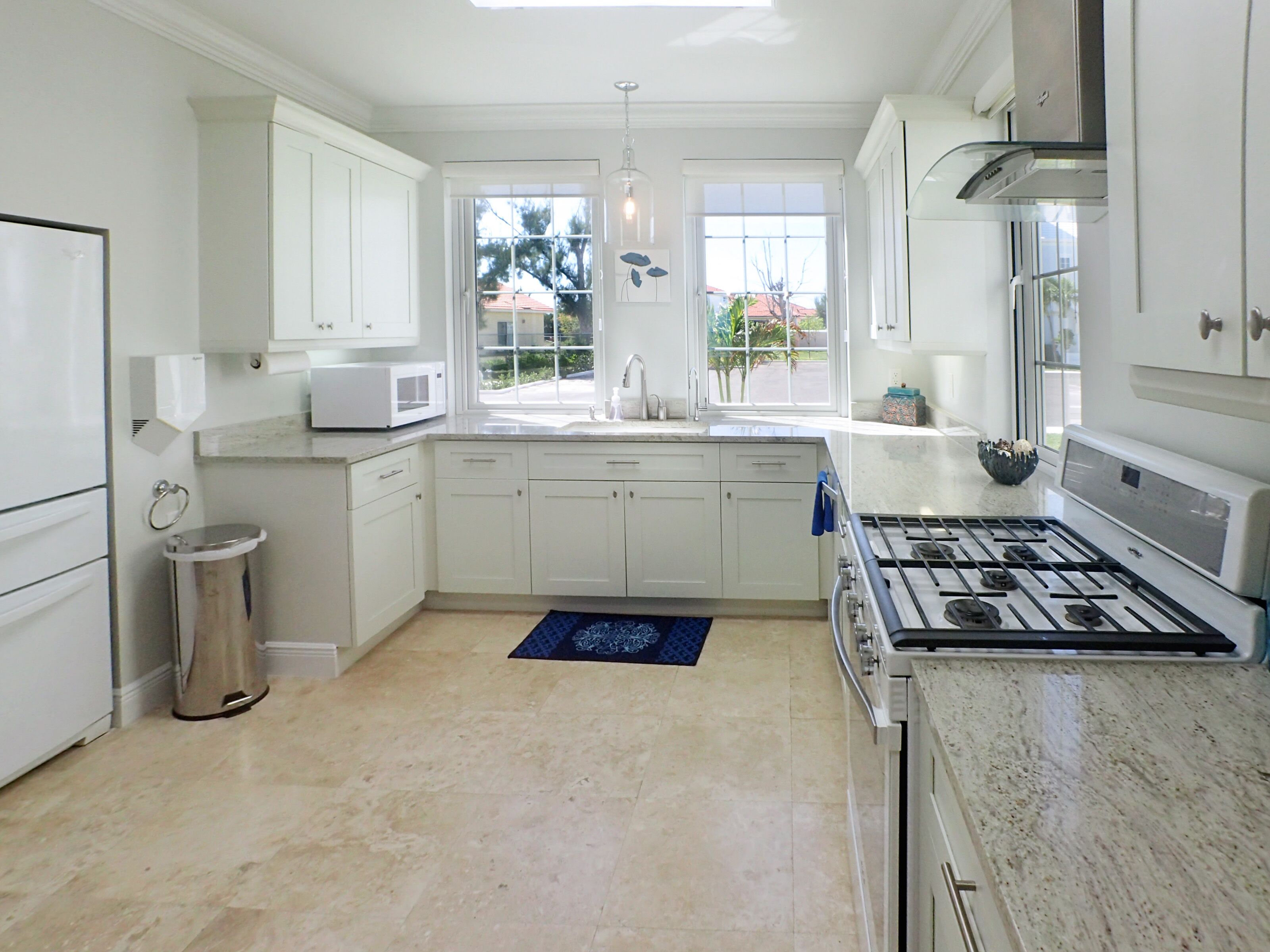 A modern kitchen with white cabinets, a stainless steel stove, and a window providing a view of the outdoors.
