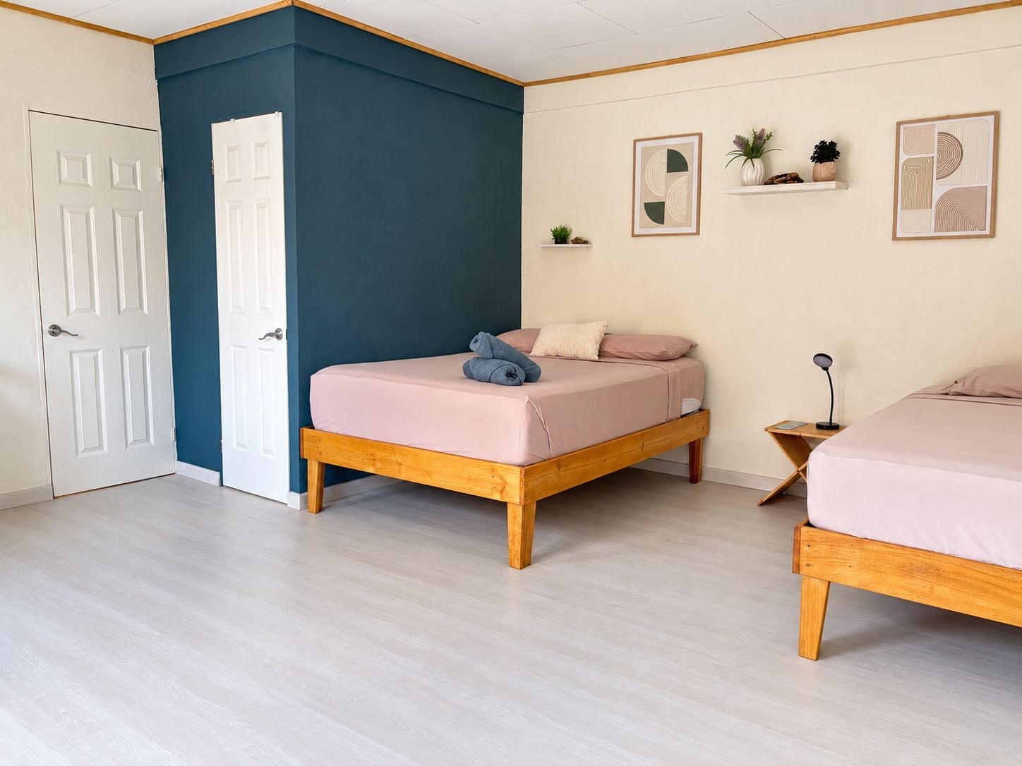 A room with two wooden beds, a white door, and a blue accent wall.