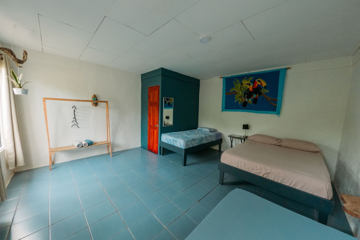 A room with a bed, a small table, a chair, a wardrobe, and a painting on the wall.