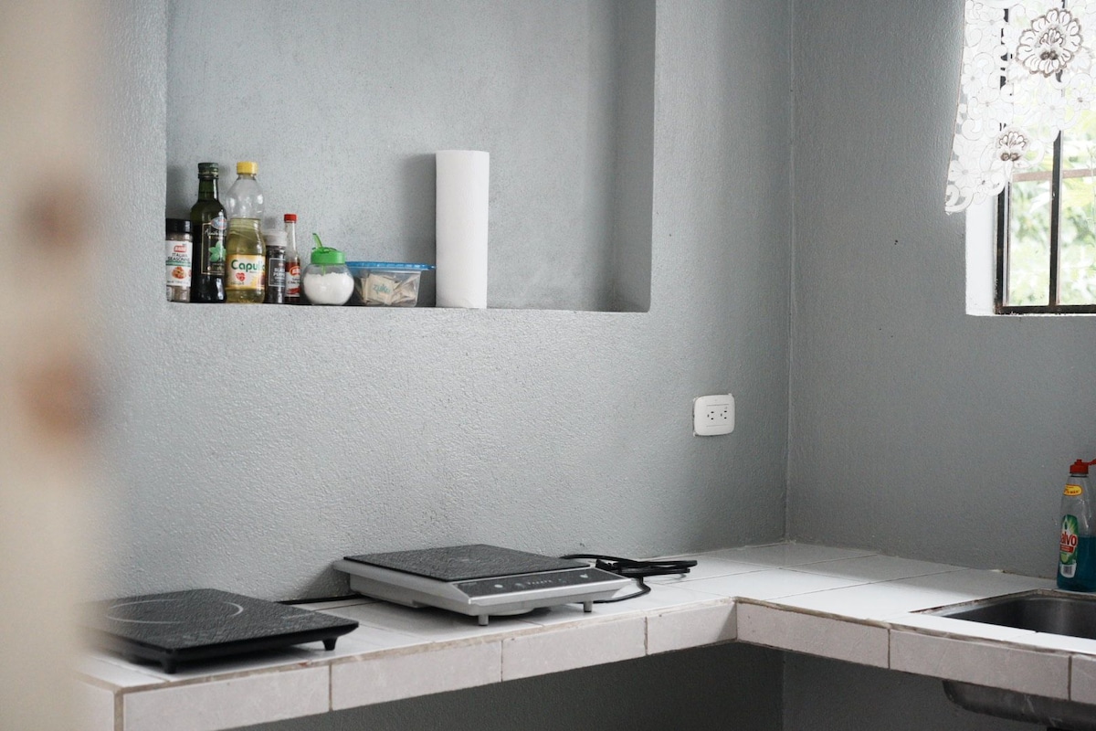 A kitchen with a white countertop, a built-in oven, and a window with a floral curtain.