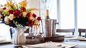 Una mesa de comedor con un centro de mesa floral, una botella de champán y un cubo de metal.