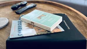 A living room with a coffee table holding a book titled 'Cambridge City Guides' and a remote control. - Cozy Regent A Apartment (Cambridge)