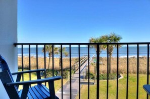 Enjoy the ocean views from this balcony with a clear view of the beach, featuring a pathway to the shore and palm trees.