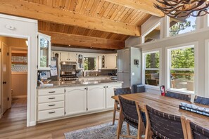 A spacious kitchen with white cabinetry, a large island, and a dining area with a wooden table and chairs.