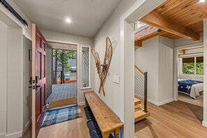 A hallway with a wooden bench, a red door, and a view of a balcony. - Mountain Dream in Homewood - Chamberlands (Homewood)