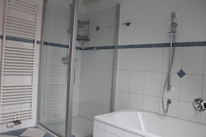 Une salle de bain avec une douche à parois de verre, une baignoire blanche et des toilettes.