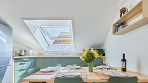 Een moderne keuken met dakraam, een eettafel gedekt voor vier personen en een wijnfles op het aanrecht.