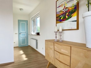 Enter a clean and functional hallway with a wooden floor, radiator, and window.