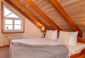 Cozy attic bedroom with a sloped ceiling, large window, and comfortable bed.