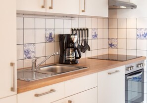 Kitchen features a coffee maker, knives, stainless steel sink, and oven.