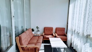 Un salon confortable avec un canapé, deux fauteuils, une petite table et une plante en pot.
