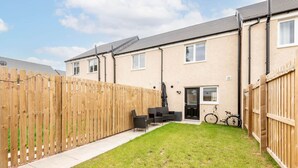 A residential property with a fenced backyard, a patio with outdoor furniture, and a bicycle. - Fort Avenue (No 31) | Guardbridge (Leuchars)