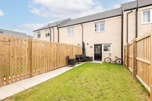 A residential property with a fenced backyard, a patio with outdoor furniture, and a bicycle. - Fort Avenue (No 31) | Guardbridge (Leuchars)