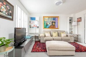 A modern living room with a flat-screen TV, a beige sofa, and a red patterned rug. - Fort Avenue (No 31) | Guardbridge (Leuchars)
