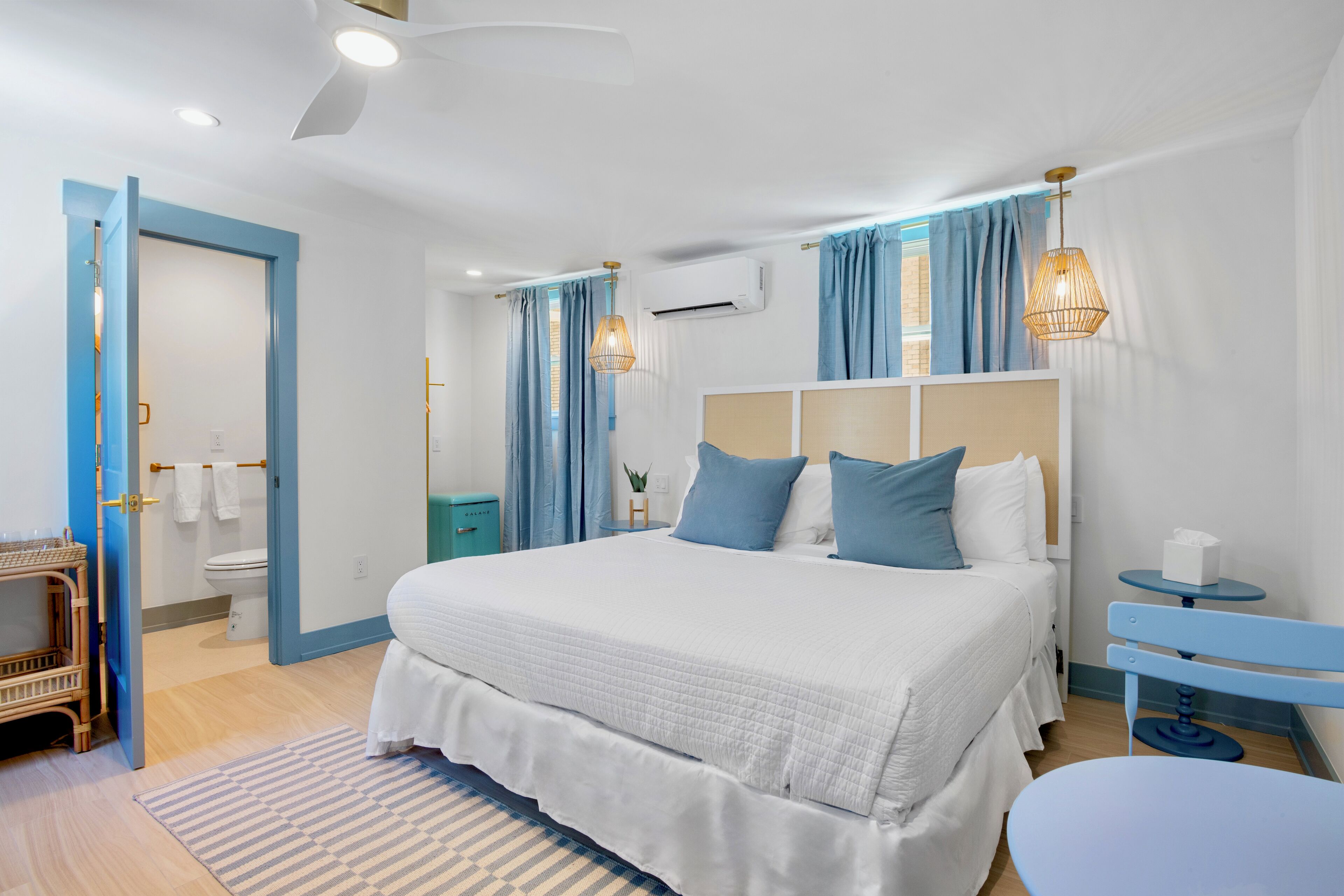 A modern bedroom with a large bed, a bedside table, a small round table, and a ceiling fan.