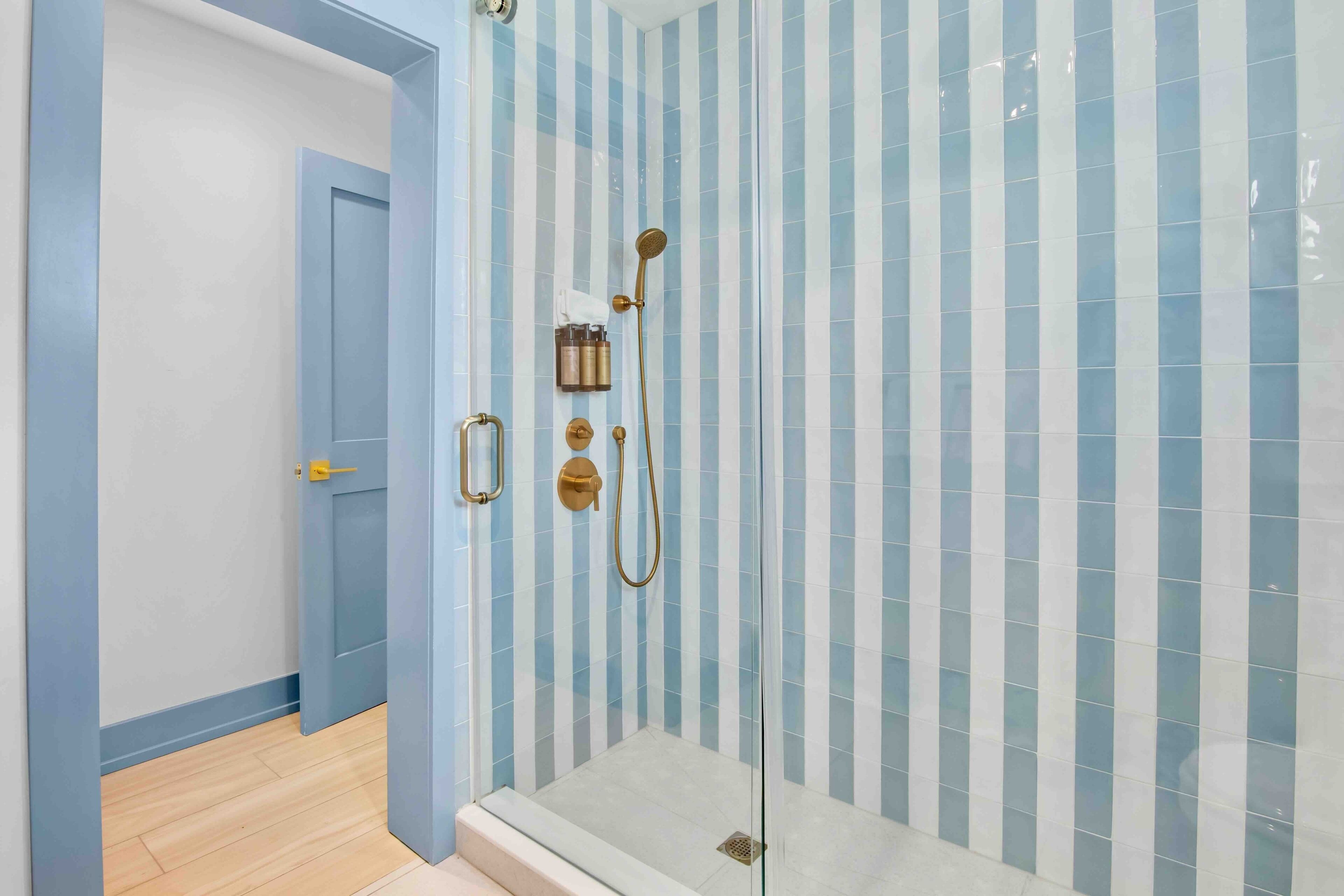 A bathroom with a shower area, a door, and a tiled wall.