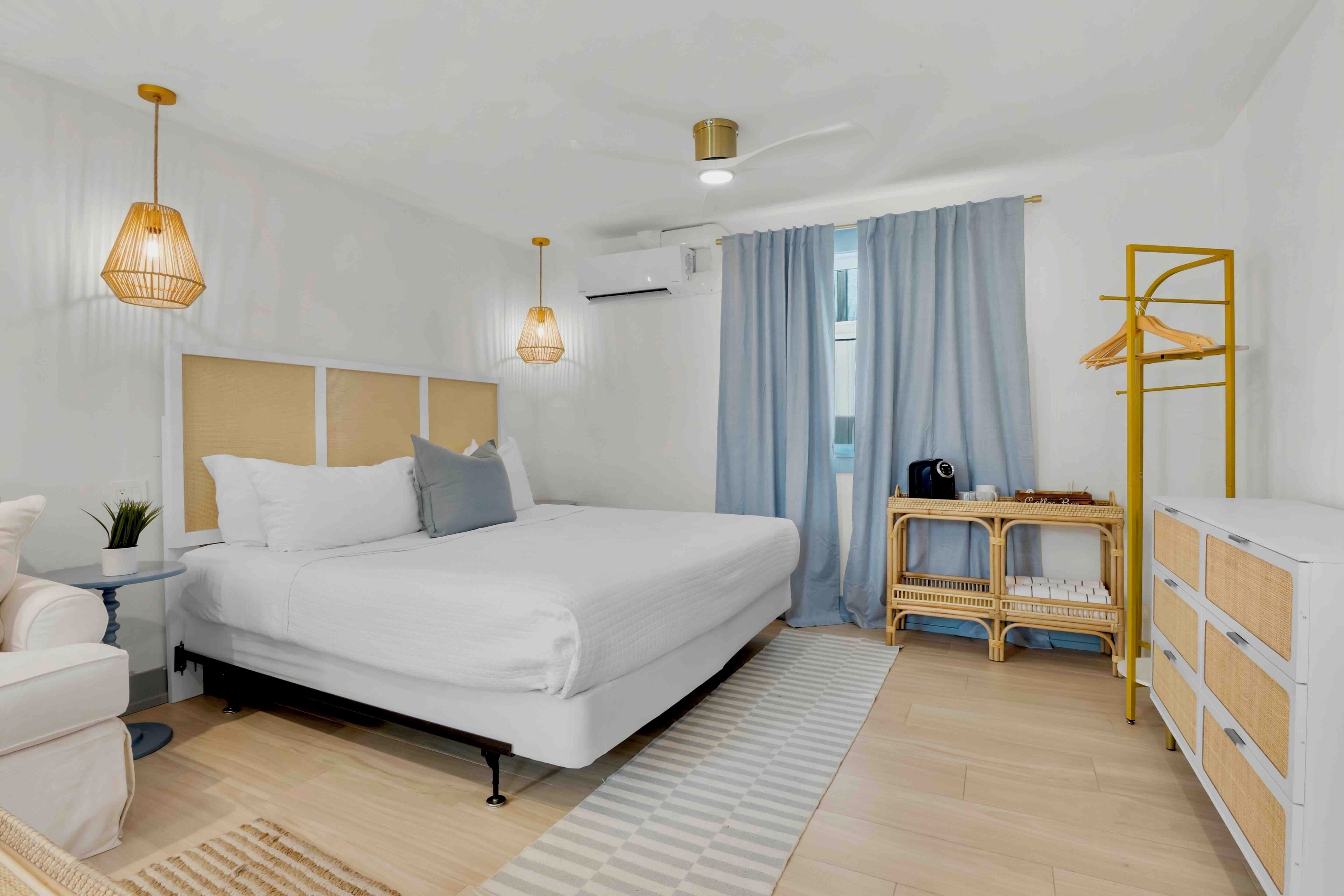 Un dormitorio moderno con una cama grande, lámparas de noche, una mesita, una silla y un armario.