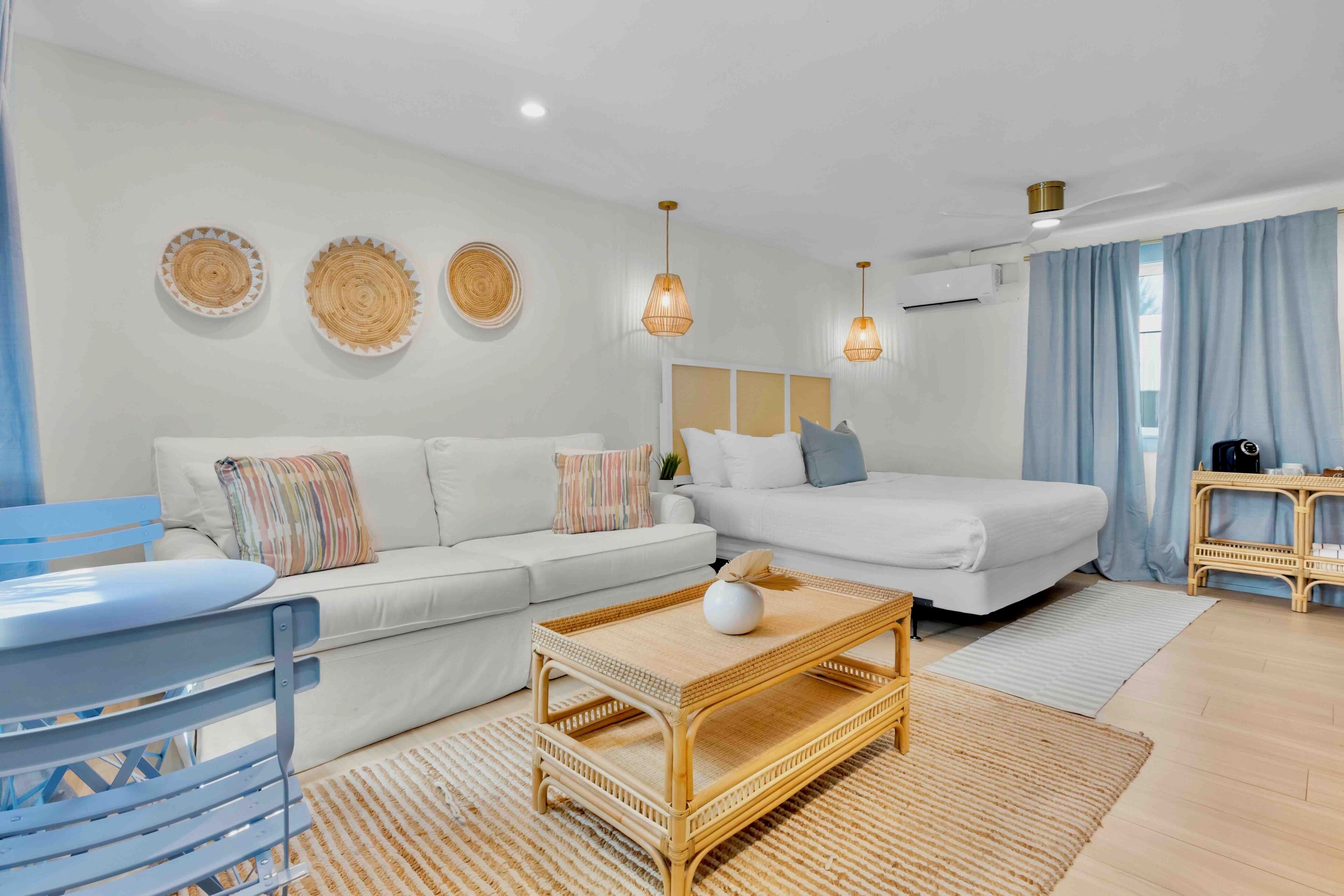 A modern hotel room with a sofa, a bed, a small table, and a wicker chair.