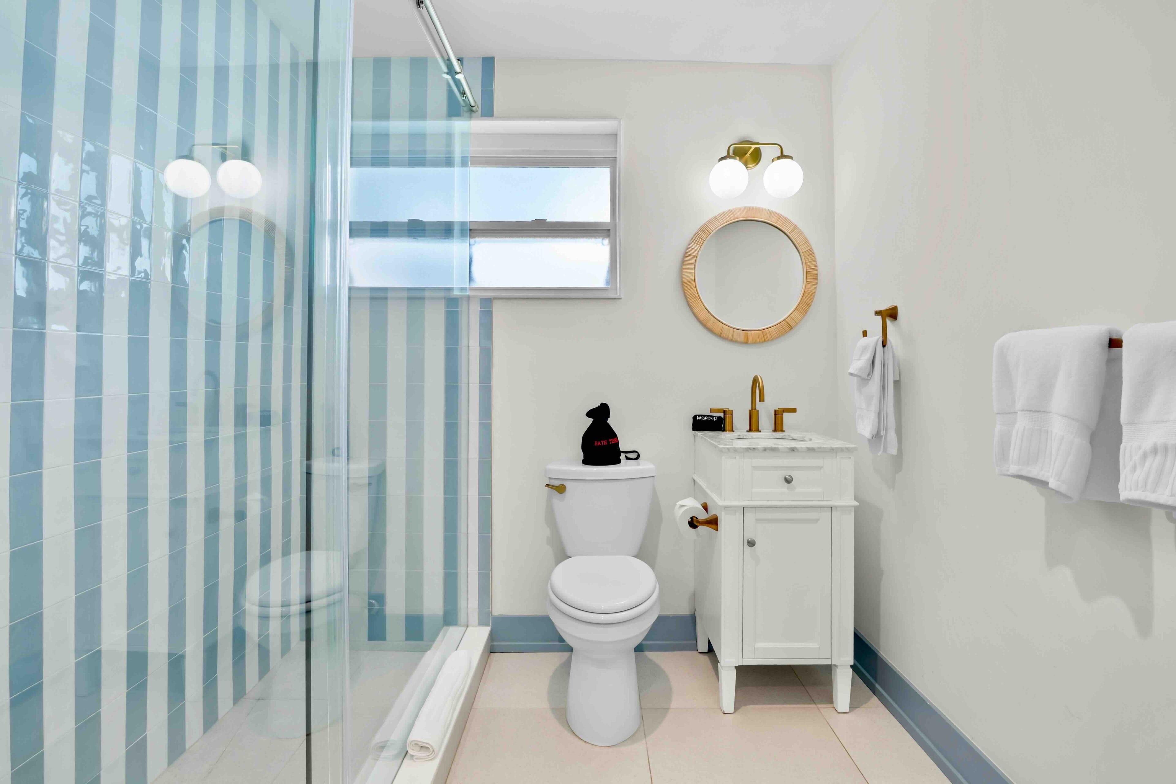 A modern bathroom with a glass shower enclosure, a toilet, a vanity with a mirror, and a towel rack.