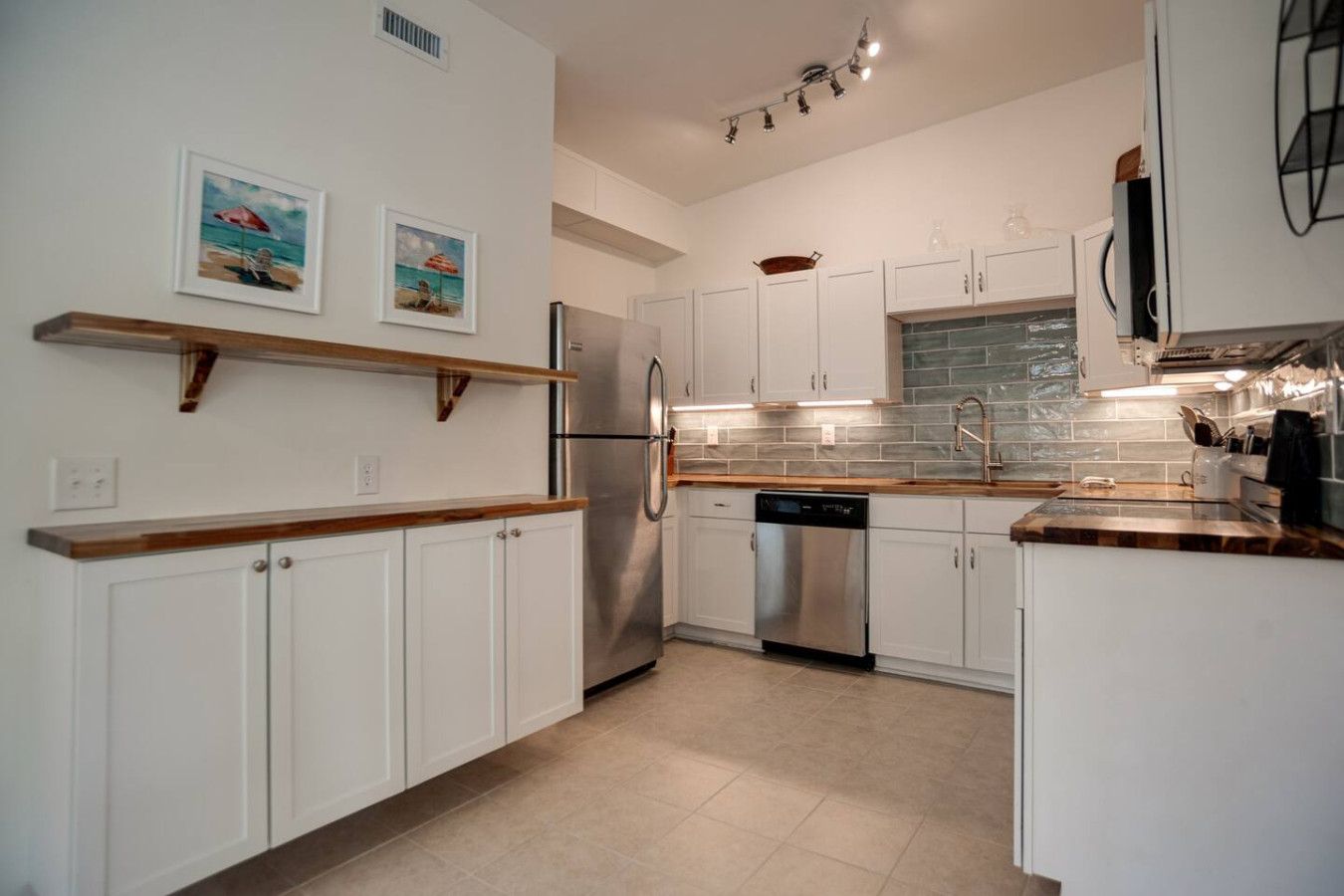 A modern kitchen with white cabinetry, stainless steel appliances, and a tiled backsplash.