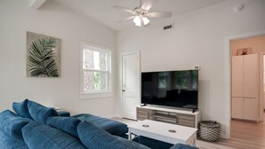 A living room with a large flat-screen TV, a ceiling fan, and a large window. - Newly Renovated Duplex- 4th Row (Hilton Head Island)