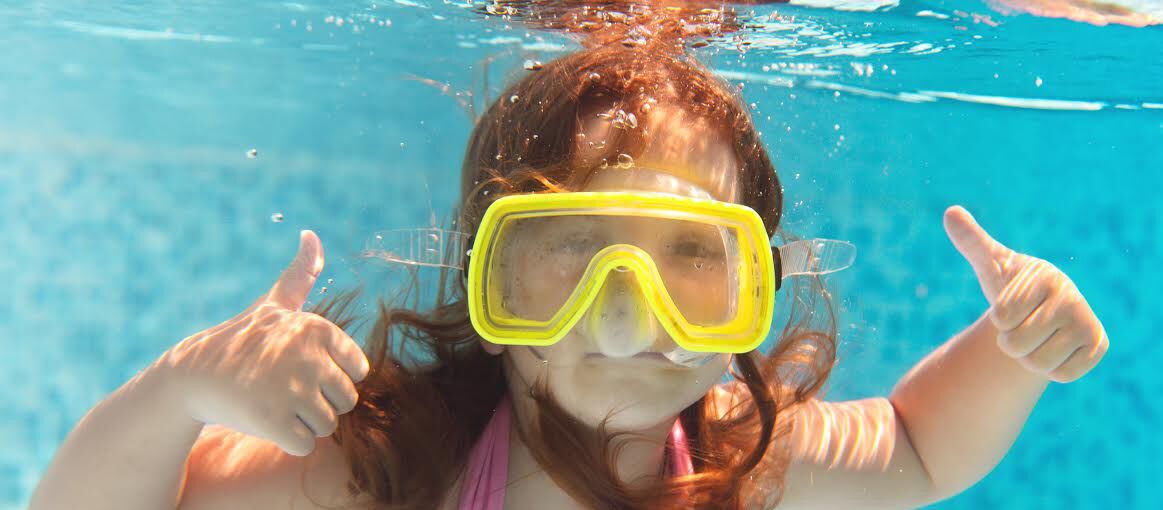 A person underwater with a pool in the background.