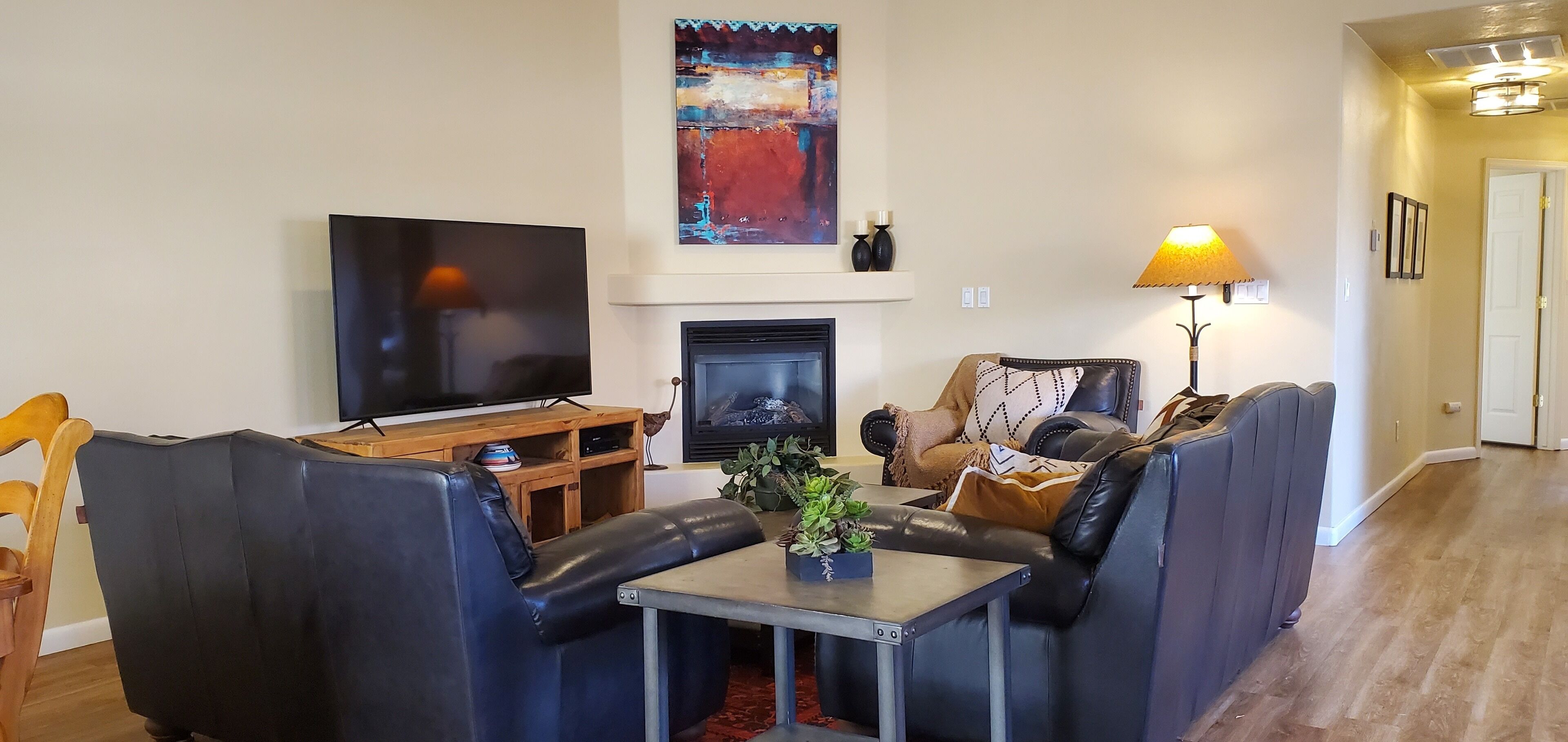 A living room with a TV, fireplace, sofa, and table.