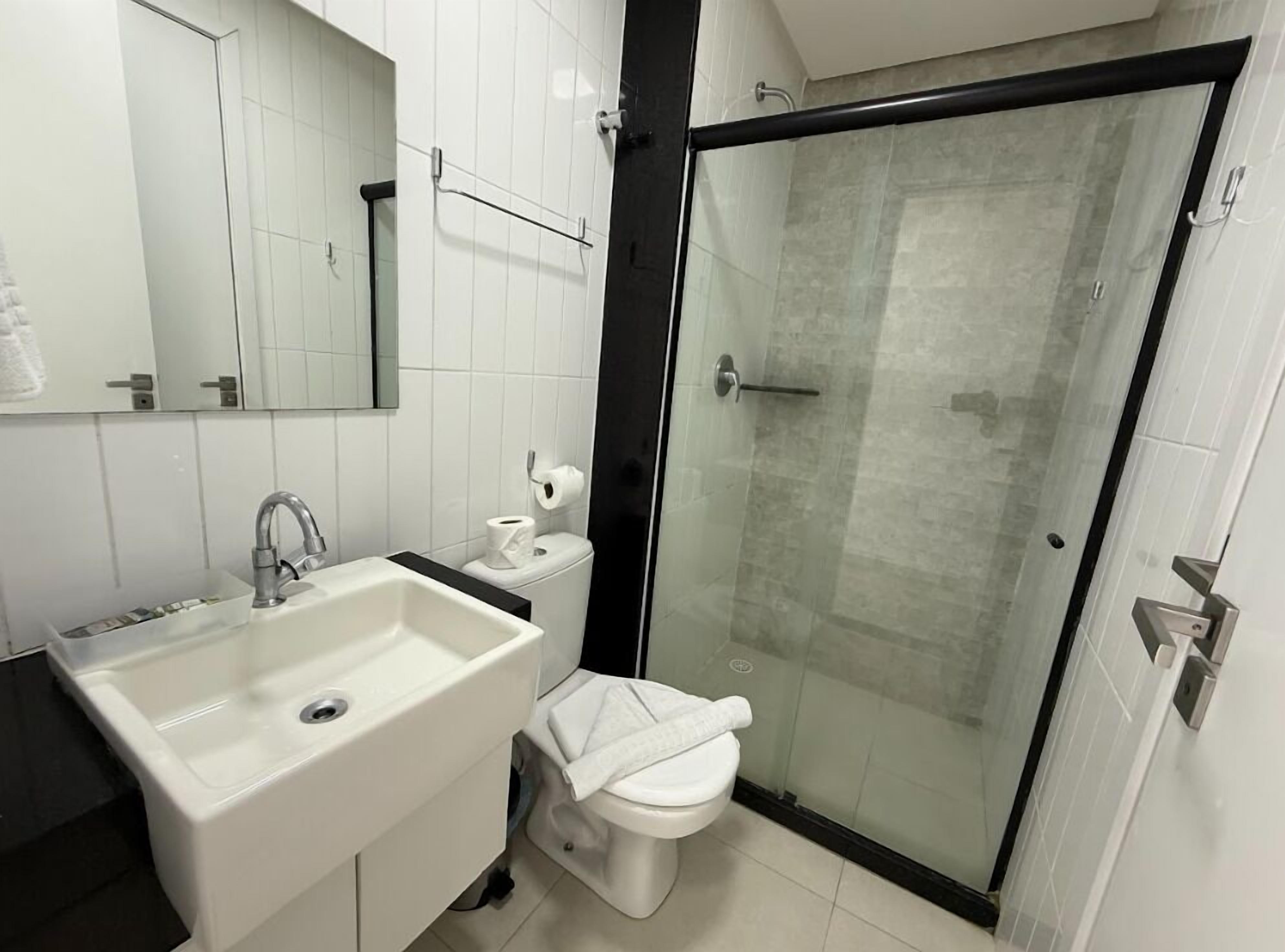 A modern bathroom with a white sink, toilet, and glass-enclosed shower.
