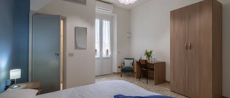 A hotel room with a bed, a desk, a wardrobe, and a chair.