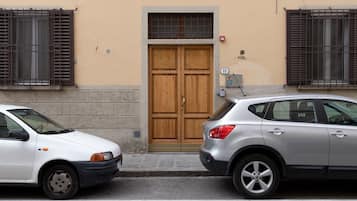 Dos coches estacionados frente a un edificio con una puerta de madera doble y ventanas con barrotes.