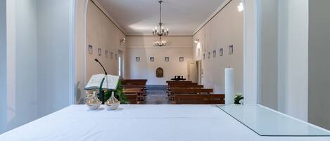 Interior de igreja com bancos, altar de mármore e vitrais.