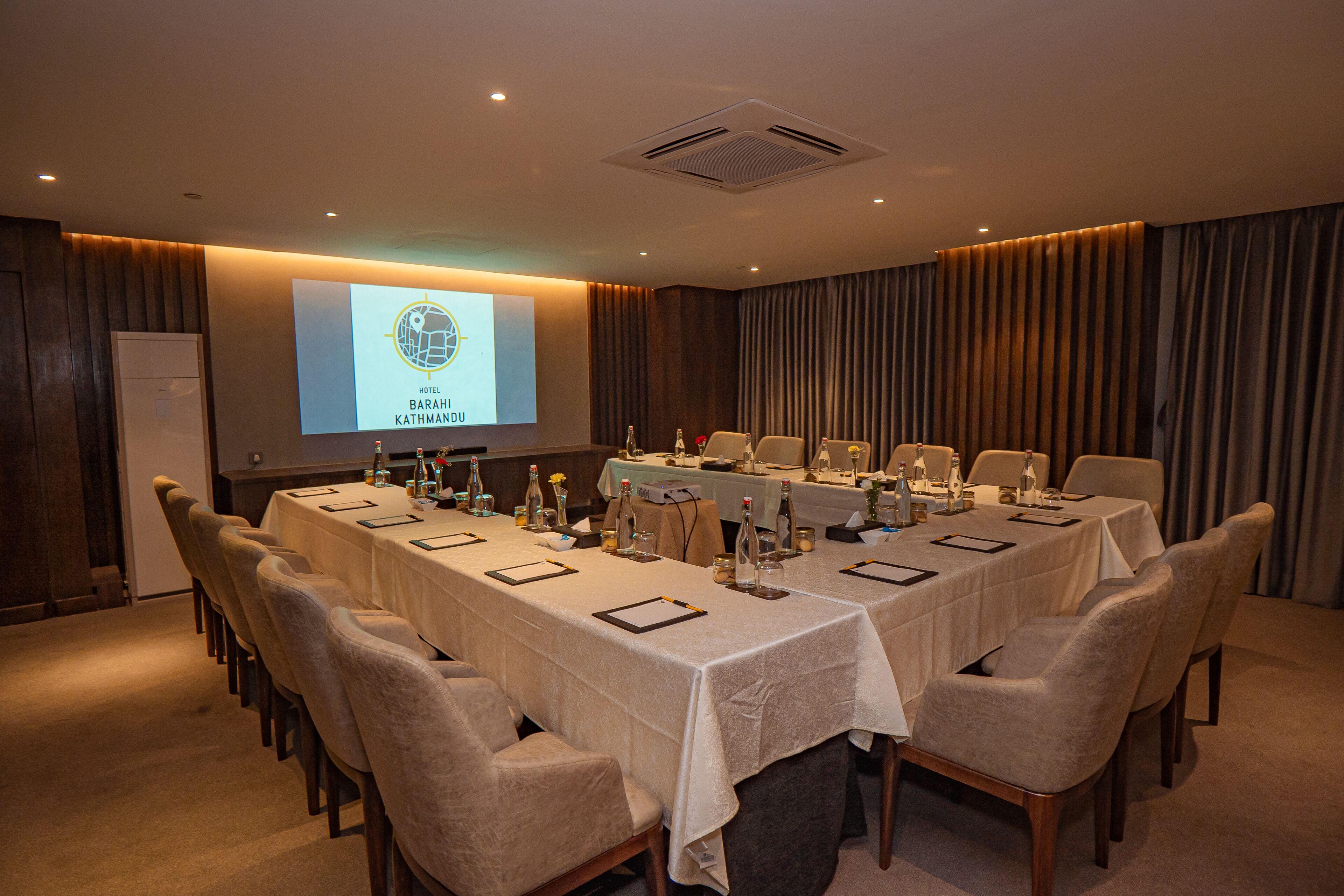 A conference room with a long table, chairs, and a presentation screen.