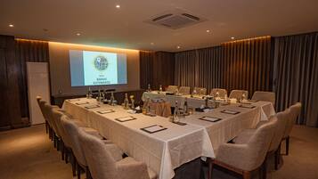A conference room with a long table, chairs, and a presentation screen.