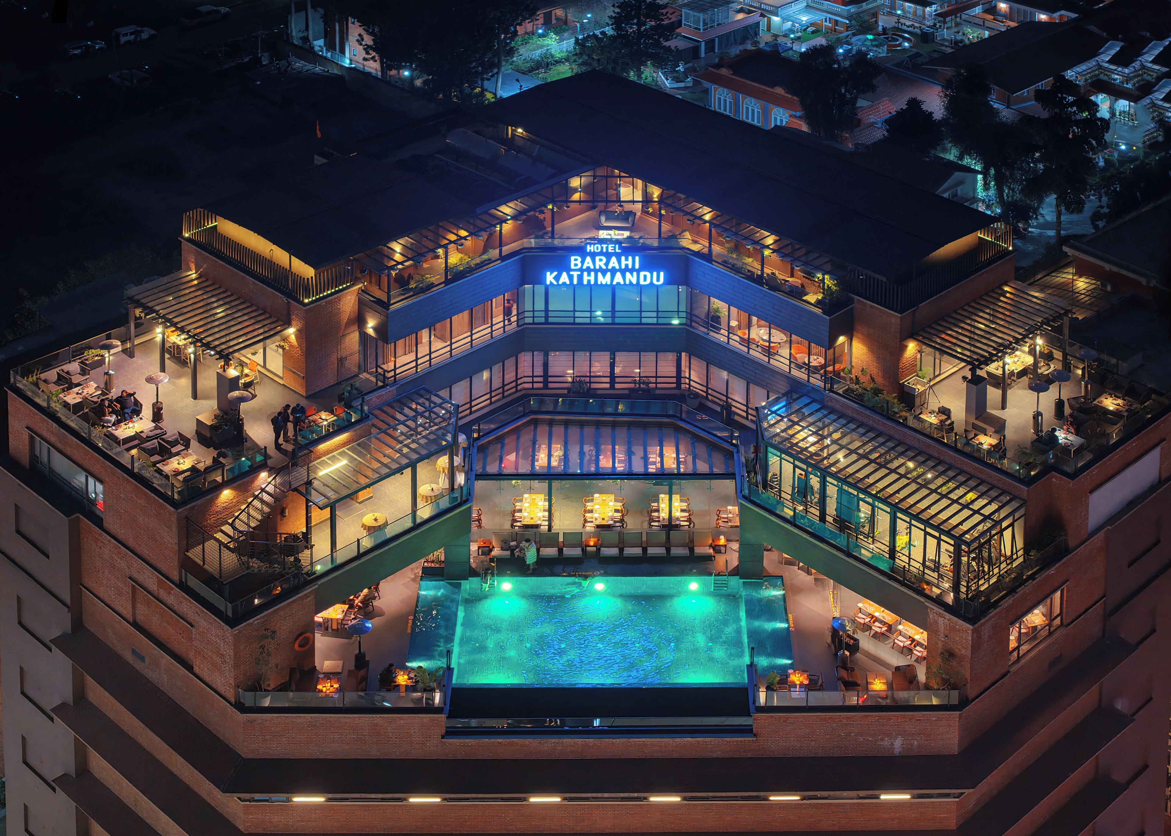 A multi-story hotel with a rooftop pool and outdoor seating areas.