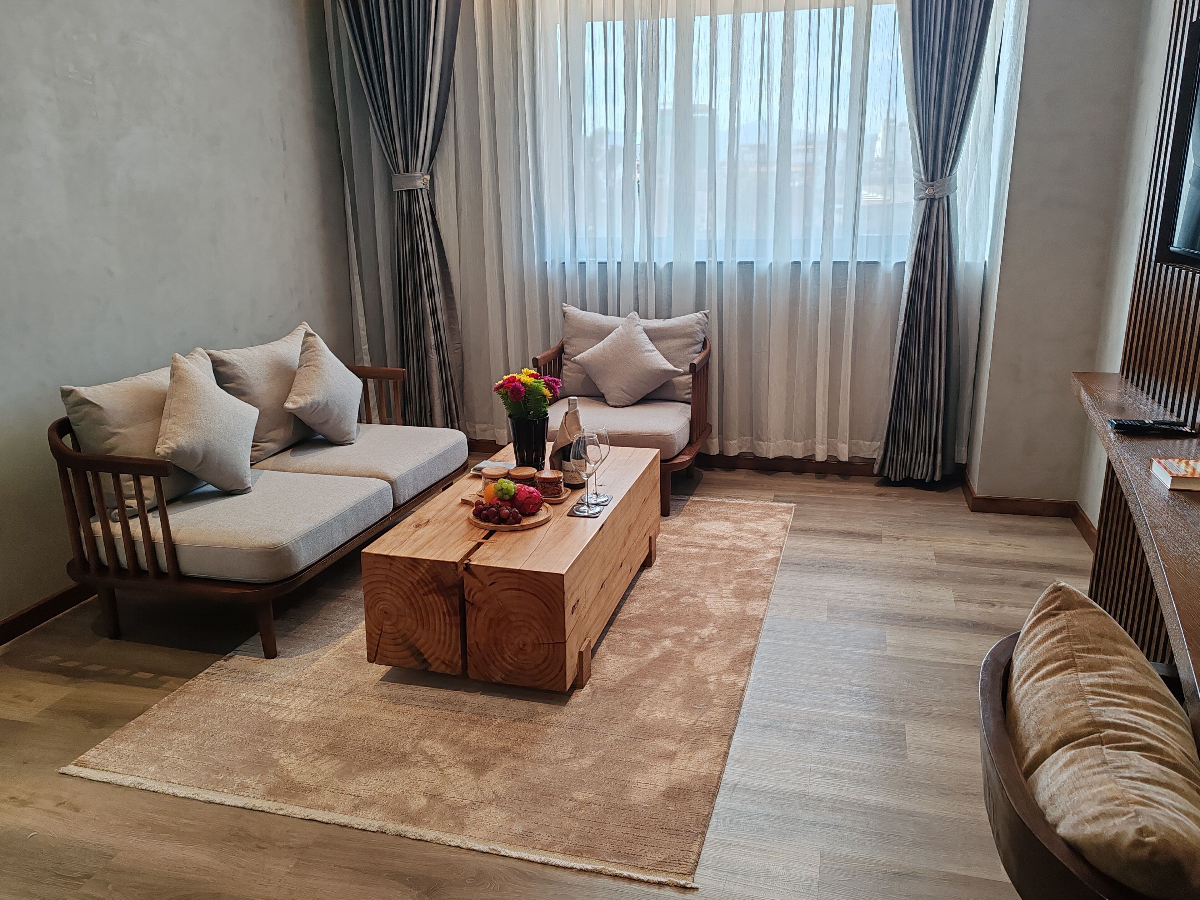 A living room with a sofa, a wooden coffee table with fruits and a glass, and a chair.