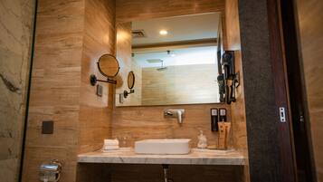 Un baño moderno con tocador de madera, un espejo grande, un lavamanos empotrado y un perchero para toallas.
