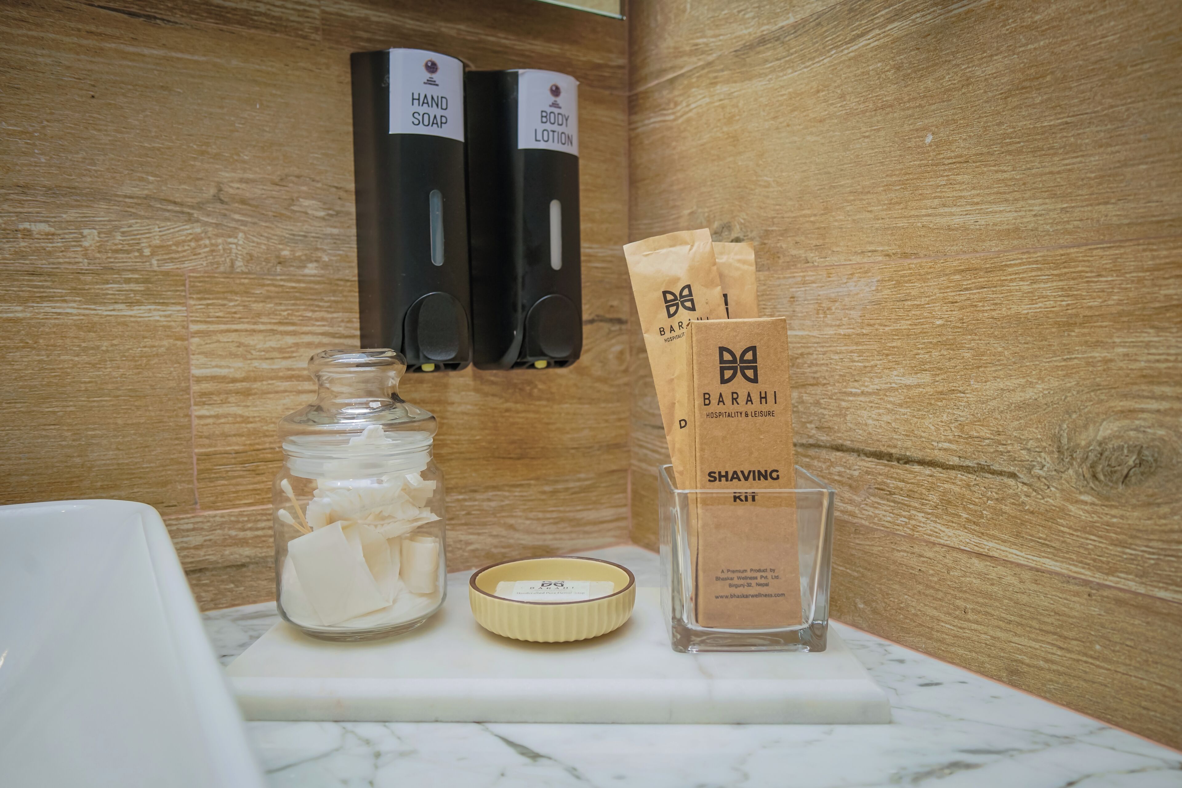 Un meuble-lavabo de salle de bain avec un distributeur de savon, un pot de cotons-tiges, un kit de rasage et un petit récipient.
