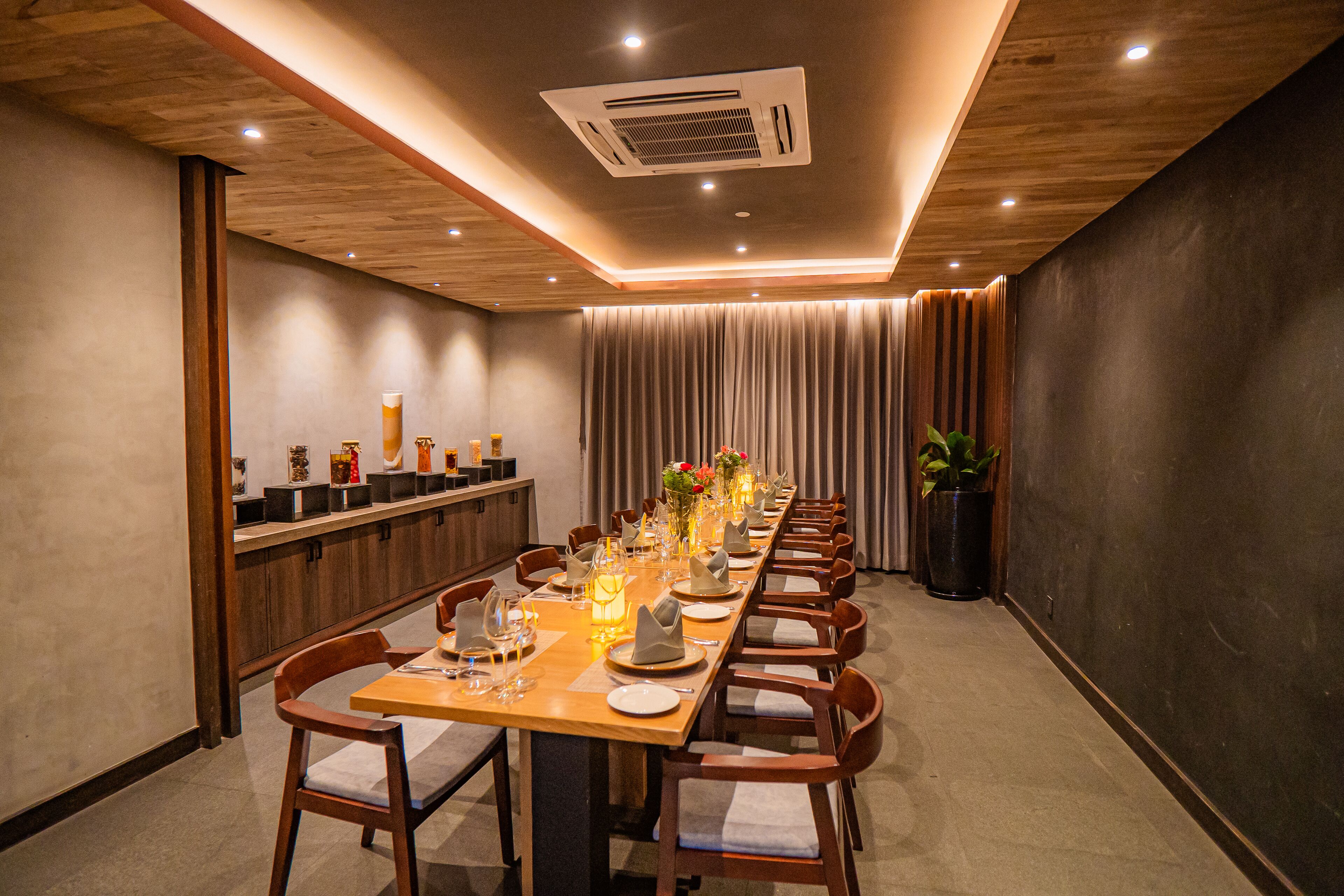 A long dining table set for a meal with chairs, a wooden ceiling, and a modern air conditioning unit.
