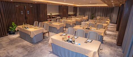 A conference room with multiple tables, chairs, and a stage area.