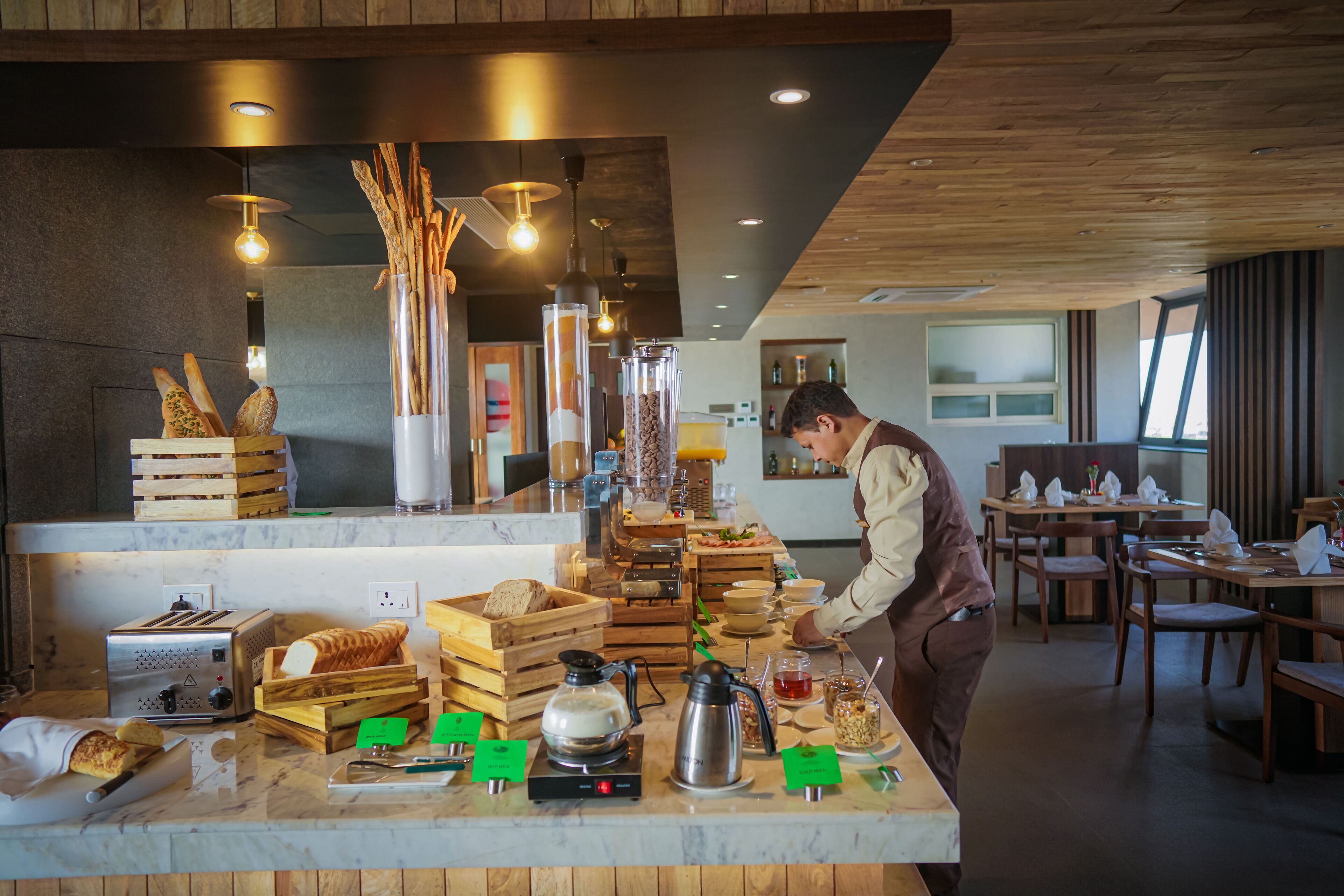 Montaje de un bufé de desayuno con diversas opciones de comida y una máquina de café.