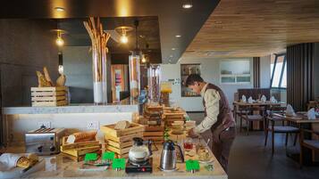 Montaje de un bufé de desayuno con diversas opciones de comida y una máquina de café.