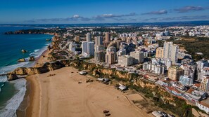 A coastal cityscape with a sandy beach, high-rise buildings, and a clear view of the ocean.