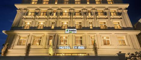 Et hotel i flere etager med klassisk arkitektur, med søjler og et tydeligt skilt med 'Treebo Trend SY Inn'.