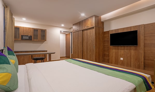 Un dormitorio con cama, escritorio, microondas y televisor.