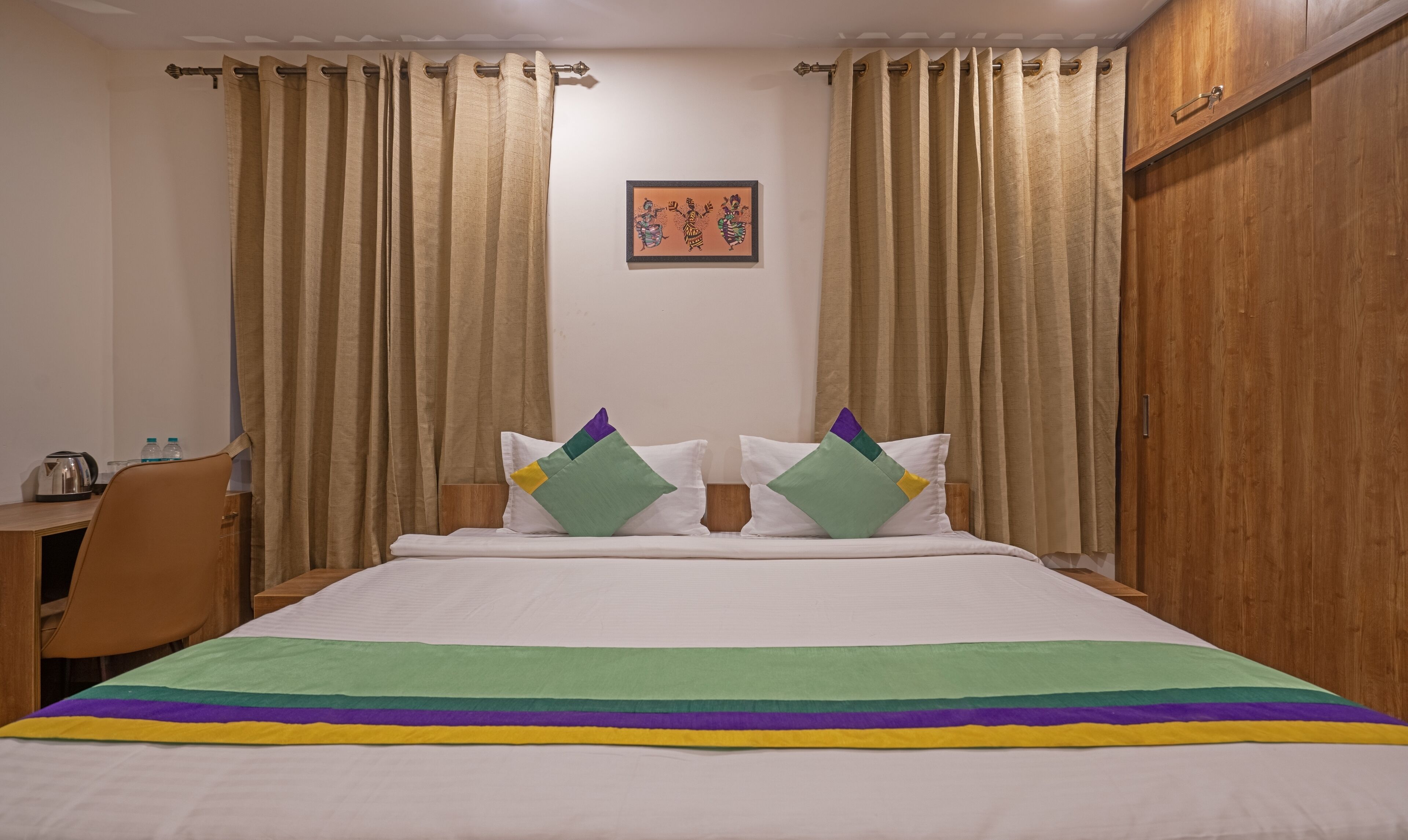 Una habitación de hotel con una cama, un escritorio con un hervidor y una silla.