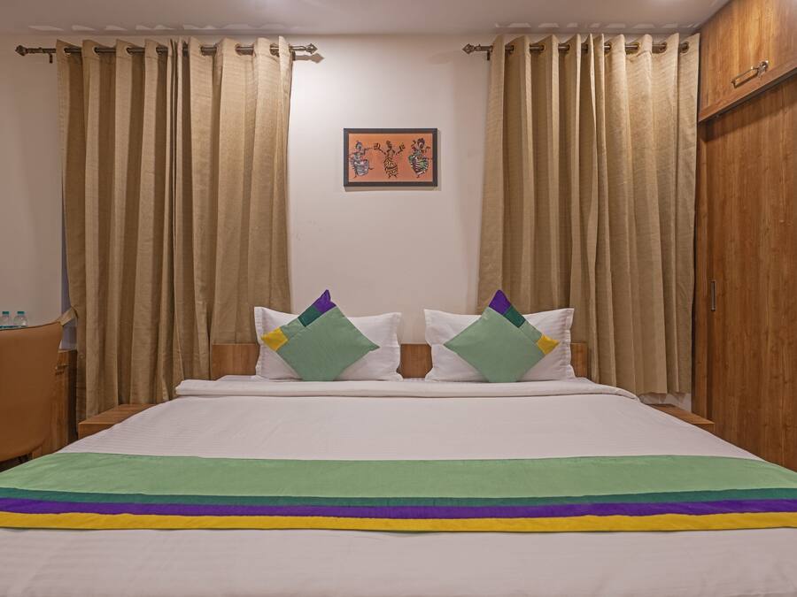 Una habitación de hotel con una cama, un escritorio con un hervidor y una silla.